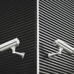 Two security cameras pointing in opposite directions against a black and white background