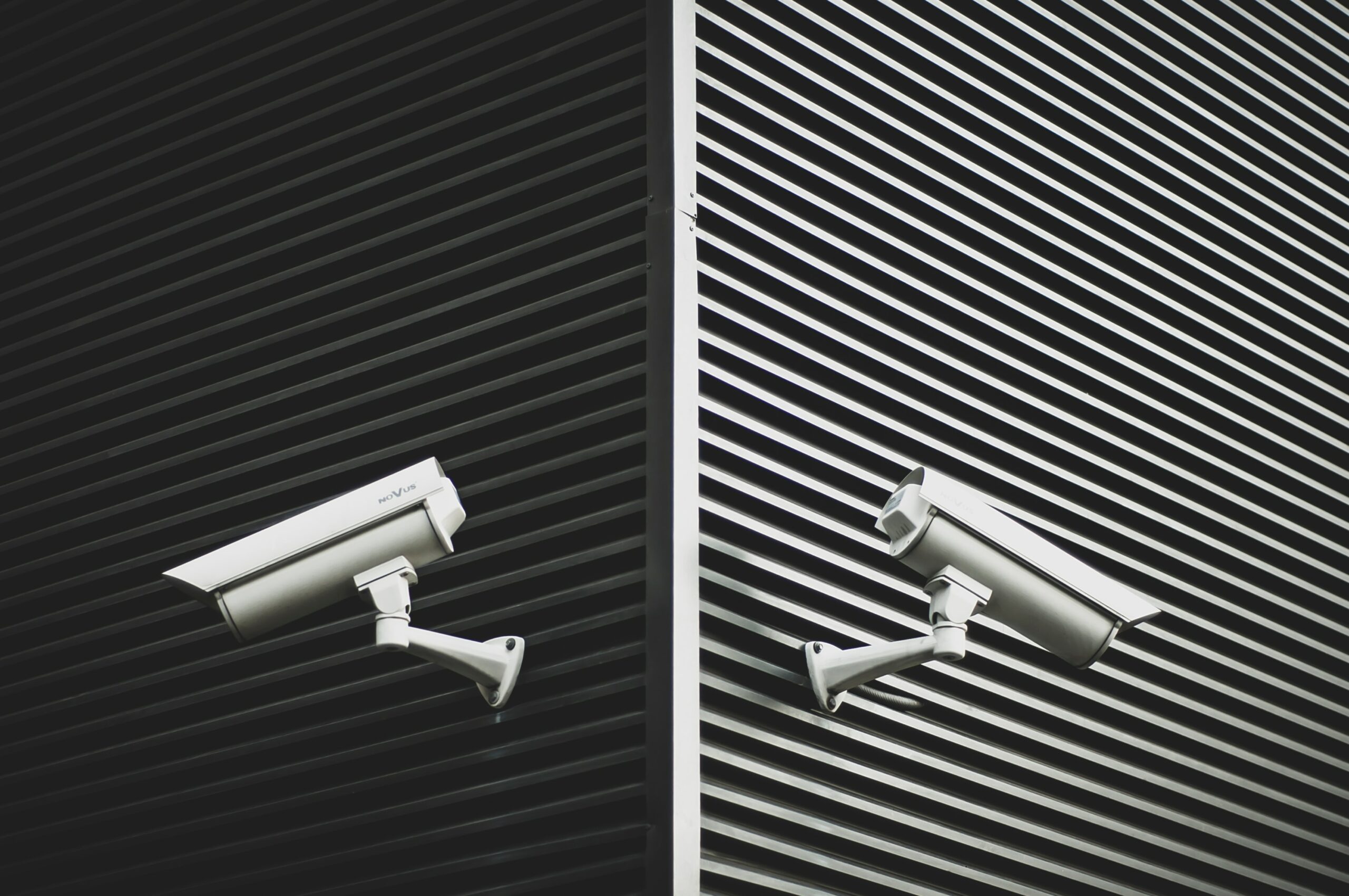 Two security cameras pointing in opposite directions against a black and white background