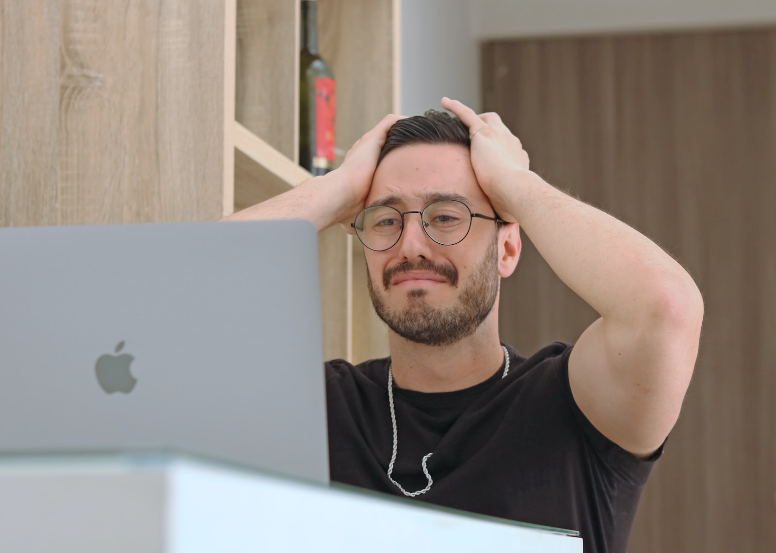 a man with glasses is looking at a laptop