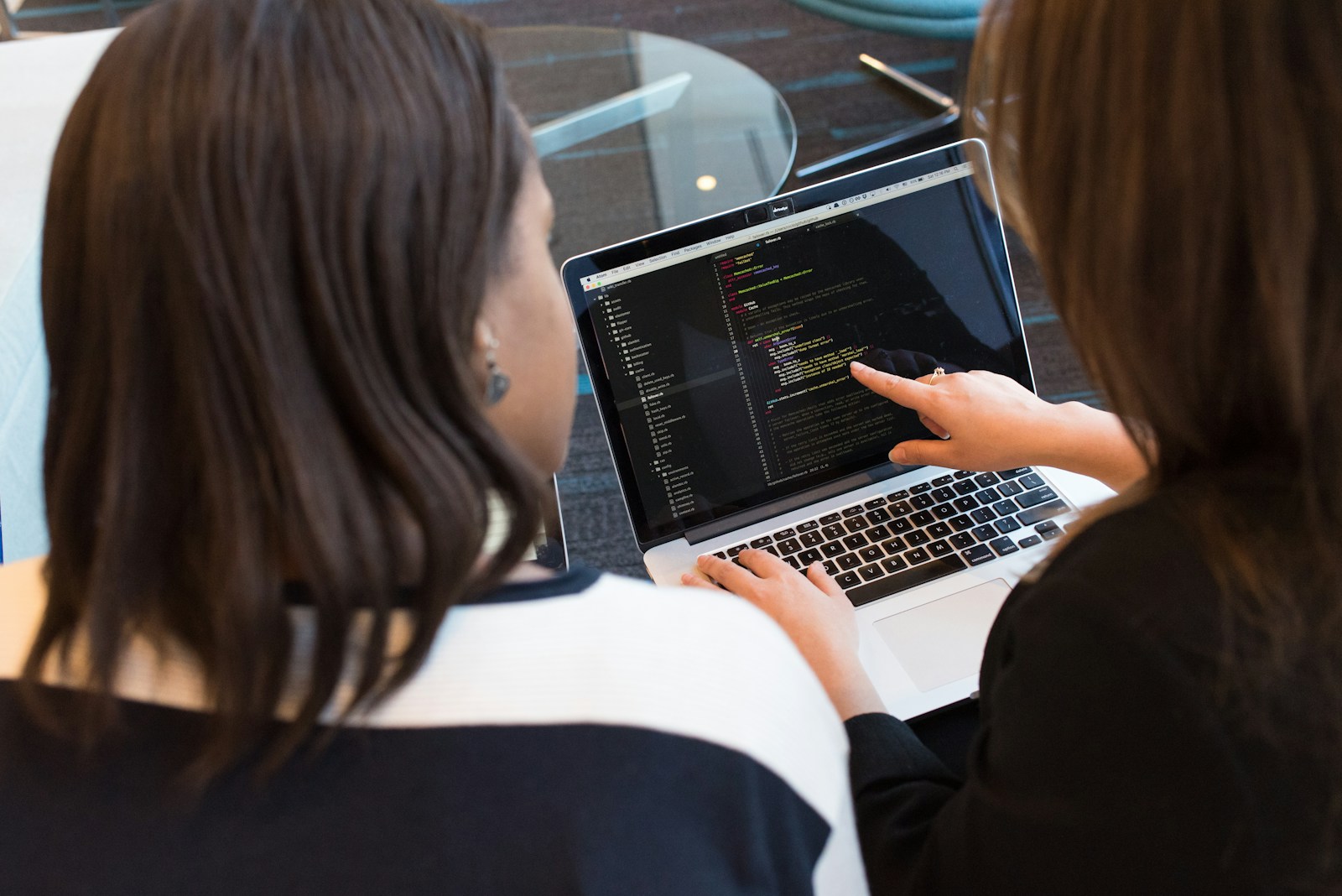 woman using MacBook Pro with person in white top